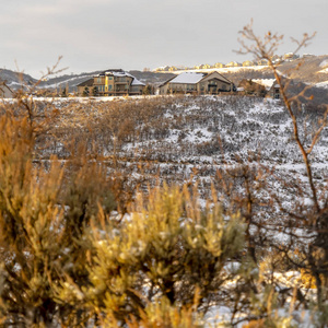 山顶上的方形框架房屋被雪地包围，天空背景多云