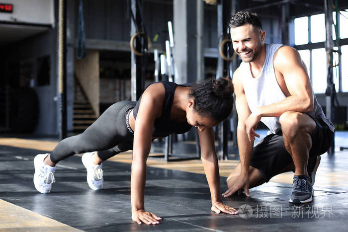 运动型女人在健身房做俯卧撑她的男朋友在看h