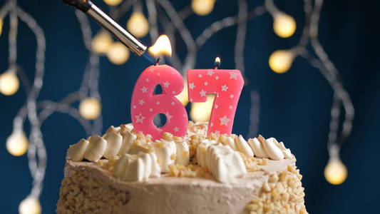 生日蛋糕，蓝色背景上有67根蜡烛，用打火机点燃。特写镜头