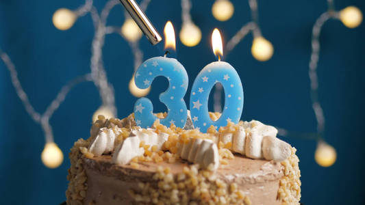 生日蛋糕，30号蜡烛，蓝色背景，打火机点燃。特写