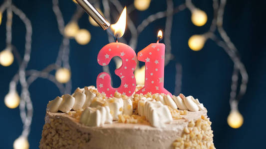 生日蛋糕,蓝色背景上有31根蜡烛,用打火机点燃.特写镜头照片