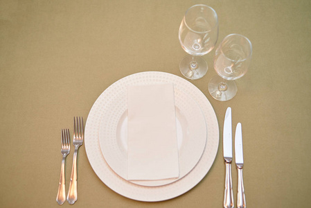 Table setting with empty white plate, napkin and cutlery on tabl