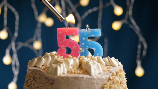 生日蛋糕，蓝色背景上有55根蜡烛，用打火机点燃。特写镜头