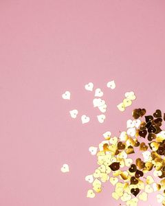 Lots of sequins in the shape of Golden hearts on a pink backgrou
