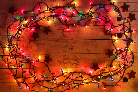 Glowing colorful Christmas lights on wooden background. Christma