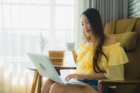 年轻的亚洲女人坐在椅子上用笔记本电脑wi