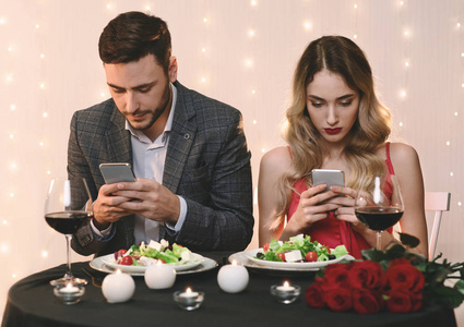 一对情侣在餐厅里用智能手机浪漫约会照片