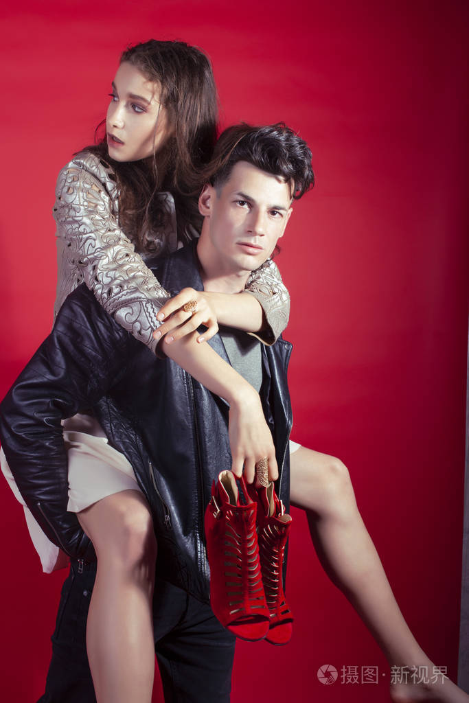 男女女在红色背景下手捧派对鞋摆造型,时尚风格让人眼前一亮照片-正版