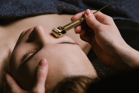 在亚洲美容诊所,按摩师手在放松女性面部肌肉.照片