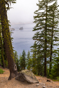 在火山口湖边的一个暴风雨天，在薄雾和树木中看到幻影船岛