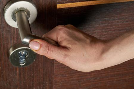女人用手打开门把手或开门.照片