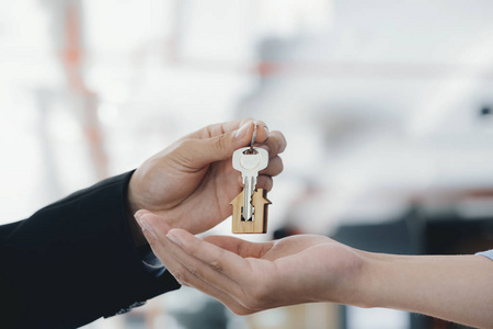 Real estate agent  holding key with house shaped keychain. 