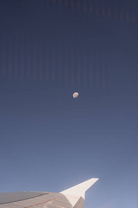 飞机机翼穿过飞机窗口，背景是月亮