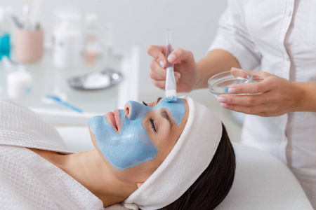 美容师在女性脸上敷蓝色面膜图片