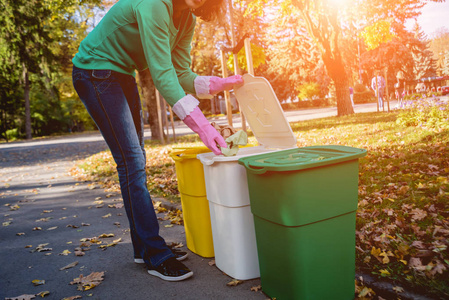 Volunteer girl sorts garbage in the street of the park. Concept 