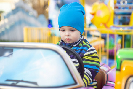 小婴儿在游乐园里开车。小司机。这孩子正在开玩具车。儿童游乐园