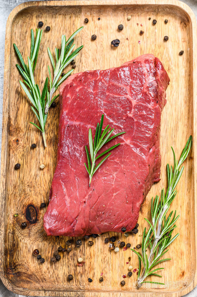 木托盘上的生臀牛排牛肉灰色背景俯视图