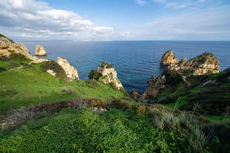 Scenic natural cliff formations of Algarve coastline with green 