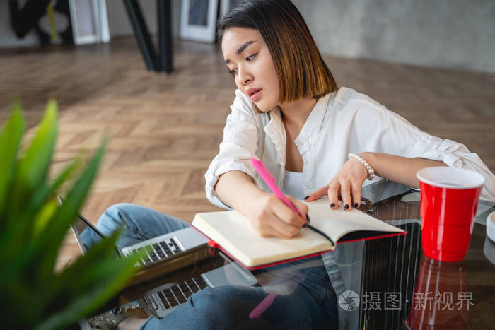 忙碌的亚洲女人在室内做笔记