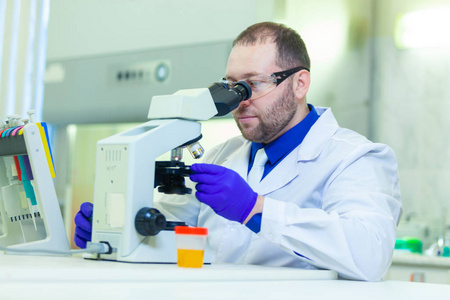 在医学实验室使用显微镜和实验室设备进行尿液分析的实验室工作者