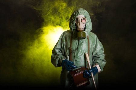 辐射和危险概念-戴防毒面具和化学防护服的人.测量放射性的工人照片