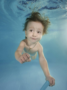 有趣的红头发男孩在游泳池水下玩玩具