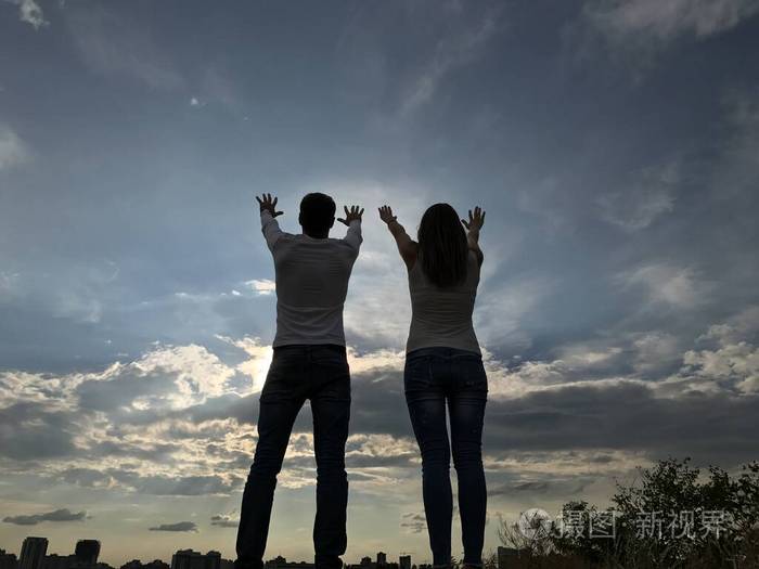 一男一女向天空举手两个恋人站在一起眺望远方