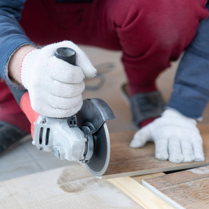 一个男人用研磨机切割瓷砖.照片