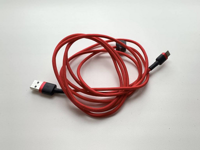 为智能手机充电的红色电源线，白色背景。手机配件，USB线。