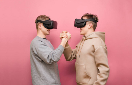 两个戴着vr头盔的欢快的游戏团队在粉红色的背景下比赛.vr游戏.照片