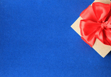 蓝色背景上带有红色丝带蝴蝶结的包装礼品盒俯视图