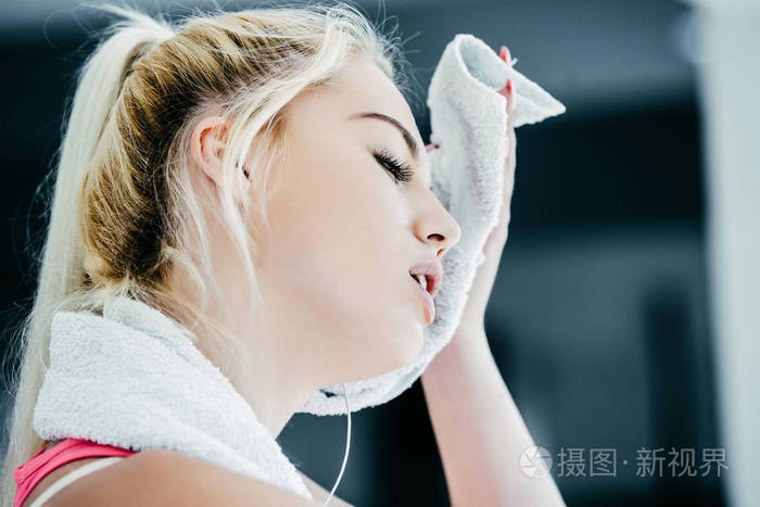 健身车上的健身女士在健身房用毛巾擦汗