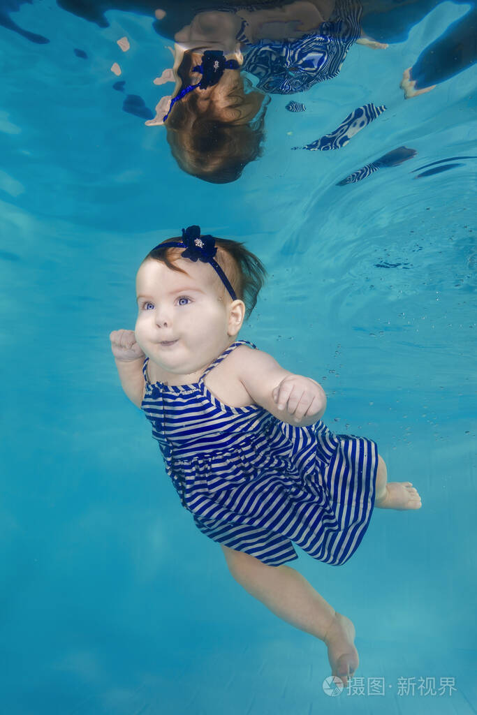 可爱的胖乎乎的小女孩穿着太阳裙潜入水下游泳池
