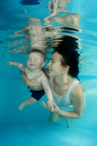 妈妈带着一个小儿子在游泳池里潜水