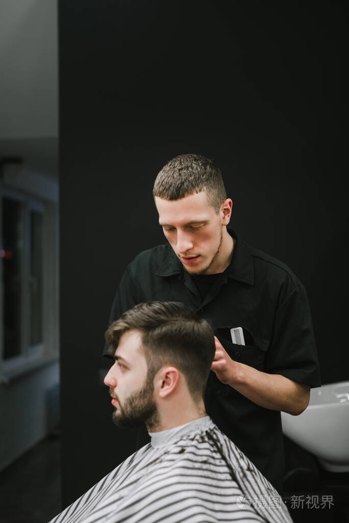 集中理发师在一家深色理发店为顾客剪剪刀