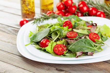 Fresh mixed salad with cherry tomatoes on white plate. 
