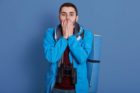 野外探险装备令人印象深刻的英俊的探险家用双手捂住嘴,直视镜头,穿着