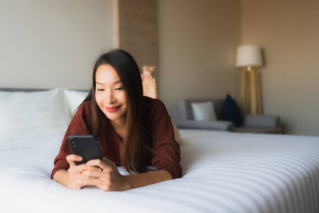 在床上用手机描绘美丽的亚洲年轻女性