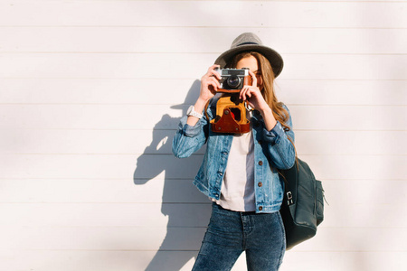 时尚女摄影师的肖像,戴着时髦的帽子,在外面用专业相机拍照.