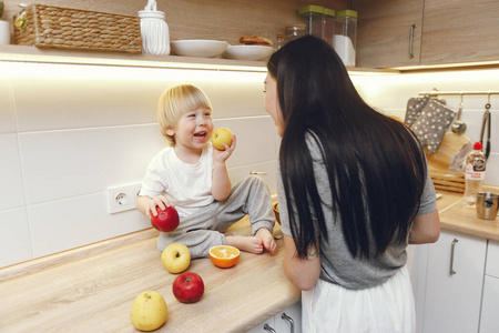 母亲带着小儿子在厨房里吃水果