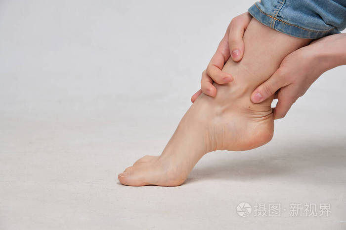 一个穿白色t恤的女孩扭伤后在按摩脚