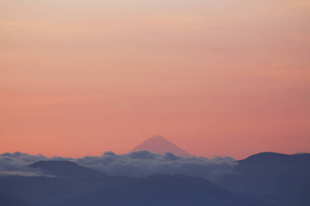 背景是云和火山的山峦轮廓危地马拉火山的景色山间日落