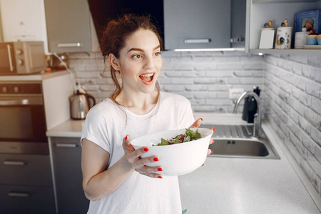 Elegant girl in a kitchen with salad