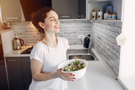 Elegant girl in a kitchen with salad