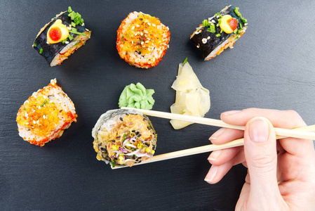 传统的日本寿司套装，用黑石制作。美味的寿司，尼吉里，萨希米和maki。一个人的美味晚餐或午餐。平铺