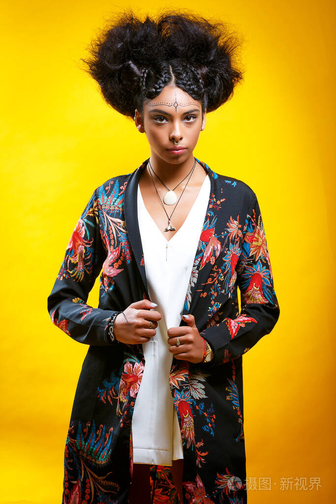 年轻的非洲女孩穿着夏季花裙在孤立的黄色背景