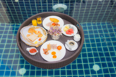 游泳池周围漂浮的早餐套餐图片