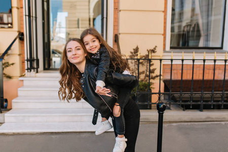 周末去野炊周末,一个漂亮的棕色头发女人背着快乐的小女孩去最喜欢的