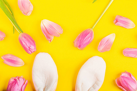 时尚的复活节背景，兔子耳朵和粉红色郁金香花。平面布置俯视图模型高架模板