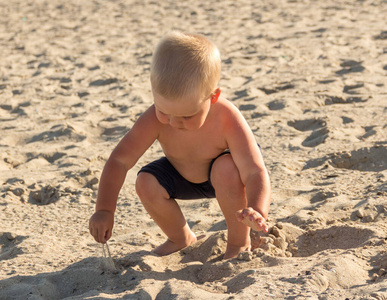 海滩上的金发男孩在玩沙子